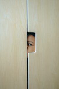 A child's curious eye peeking through a closet door indoors.